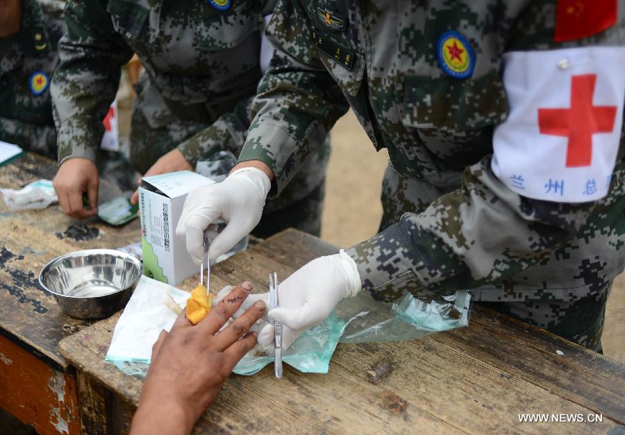 An injured villager has his fingers treated by military health workers in the quake-hit Yongxing Village, Meichuan Township, Minxian County, northwest China's Gansu Province, July 23, 2013. An emergency team of health workers sent by a military hospital in Gansu arrived in Minxian after a 6.6-magnitude earthquake jolted the province on Monday. They have received some 60 severely wounded people. (Xinhua/Jin Liangkuai)