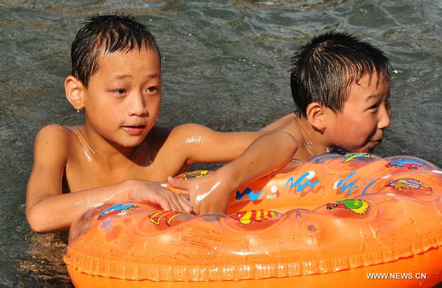 Children enjoy coolness in the Tuojiang River in Fenghuang ancient town, central China's Hunan Province, July 23, 2013. The provincial meteorological observatory issued an orange alert for high temperatures in Hunan, estimating that the highest temperature will reach 37 degrees Celsius in most pasts of the province. (Xinhua/Long Hongtao)