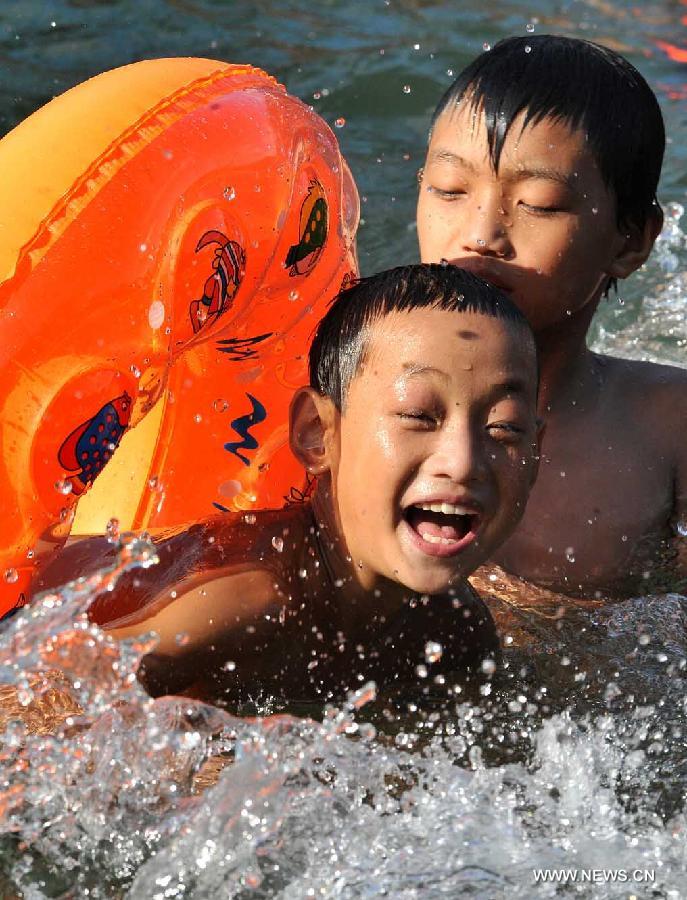 Children enjoy coolness in the Tuojiang River in Fenghuang ancient town, central China's Hunan Province, July 23, 2013. The provincial meteorological observatory issued an orange alert for high temperatures in Hunan, estimating that the highest temperature will reach 37 degrees Celsius in most pasts of the province. (Xinhua/Long Hongtao)