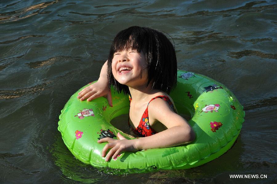 A girl enjoys coolness in the Tuojiang River in Fenghuang ancient town, central China's Hunan Province, July 23, 2013. The provincial meteorological observatory issued an orange alert for high temperatures in Hunan, estimating that the highest temperature will reach 37 degrees Celsius in most pasts of the province. (Xinhua/Long Hongtao)