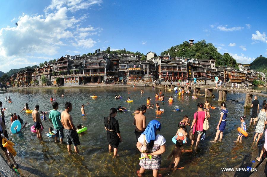 Tourists enjoy coolness in the Tuojiang River in Fenghuang ancient town, central China's Hunan Province, July 23, 2013. The provincial meteorological observatory issued an orange alert for high temperatures in Hunan, estimating that the highest temperature will reach 37 degrees Celsius in most pasts of the province. (Xinhua/Long Hongtao)