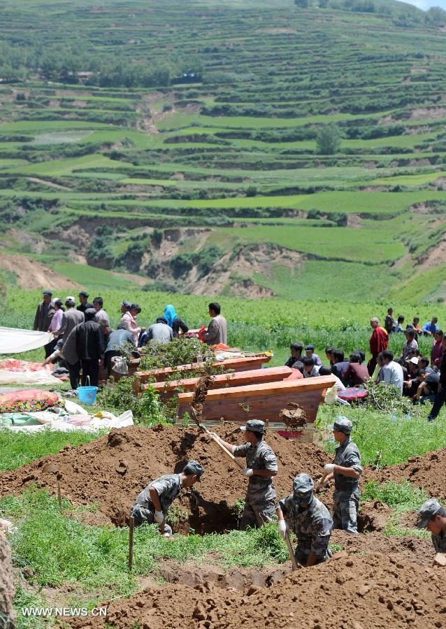 Rescuers dig holes to place coffins during the funeral held for victims killed in the deadly earthquake in Yongguang Village, Meichuan Township, Minxian County, northwest China's Gansu Province, July 23, 2013. Twelve bodies buried in ruins in the village were digged out, and their relatives held funerals for them on Tuesday. (Xinhua/Luo Xiaoguang)