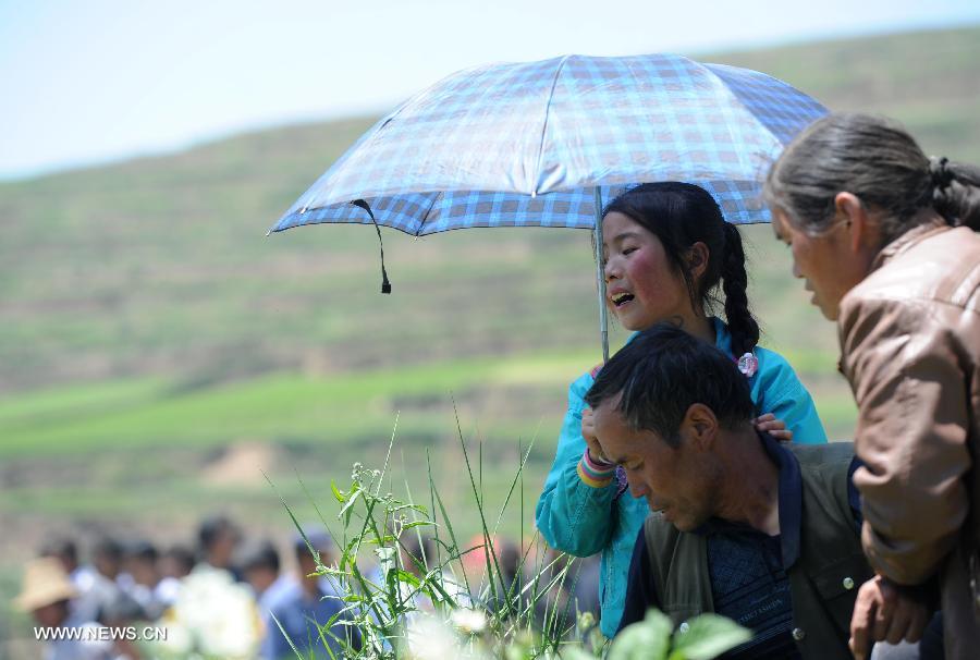 People weep during the funeral held for their relatives killed in the deadly earthquake in Yongguang Village, Meichuan Township, Minxian County, northwest China's Gansu Province, July 23, 2013. Twelve bodies buried in ruins in the village were digged out, and their relatives held funerals for them on Tuesday. (Xinhua/Luo Xiaoguang)