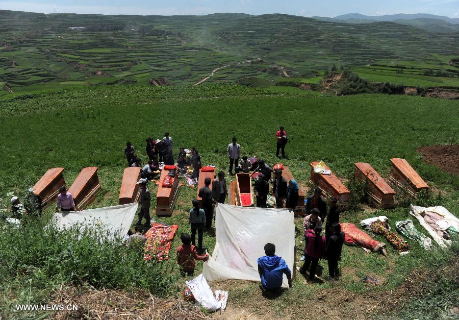 Coffins are seen at the funeral held for victims killed in the deadly earthquake in Yongguang Village, Meichuan Township, Minxian County, northwest China's Gansu Province, July 23, 2013. Twelve bodies buried in ruins in the village were digged out, and their relatives held funerals for them on Tuesday. (Xinhua/Luo Xiaoguang)