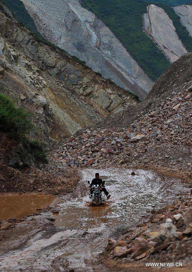A villager rides a motorcycle at quake-hit Meichuan Township of Minxian County, northwest China's Gansu Province, July 23, 2013. The death toll has climbed to 94 in the 6.6-magnitude earthquake which jolted a juncture region of Minxian County and Zhangxian County in Dingxi City Monday morning. (Xinhua/Liu Xiao)