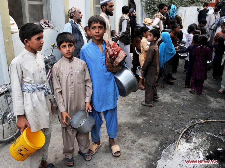 Afghan children wait to receive food donated by rich people during holy month of Ramadan in Nangarhar province in eastern Afghanistan on July 23, 2013. (Xinhua/Tahir Saf)