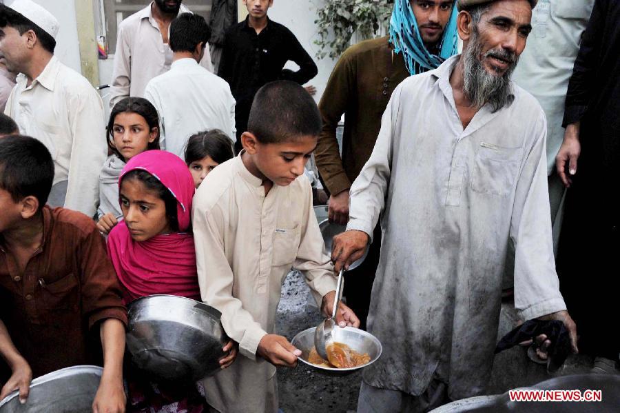 Afghan children receive food donated by rich people during holy month of Ramadan in Nangarhar province in eastern Afghanistan on July 23, 2013. (Xinhua/Tahir Saf) 
