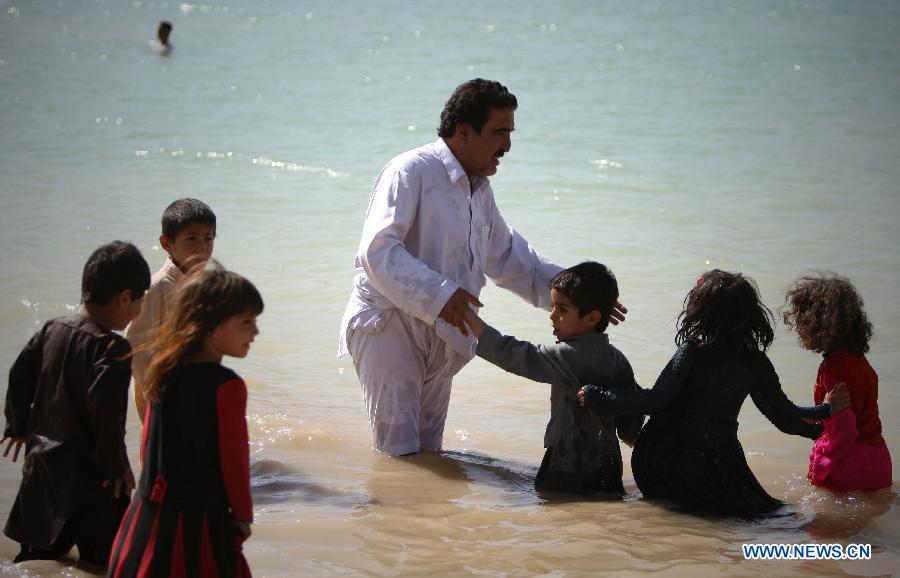 An Afghan man and his children cool themselves at a canal in Kabul, Afghanistan, on July 23, 2013. (Xinhua/Ahmad Massoud)