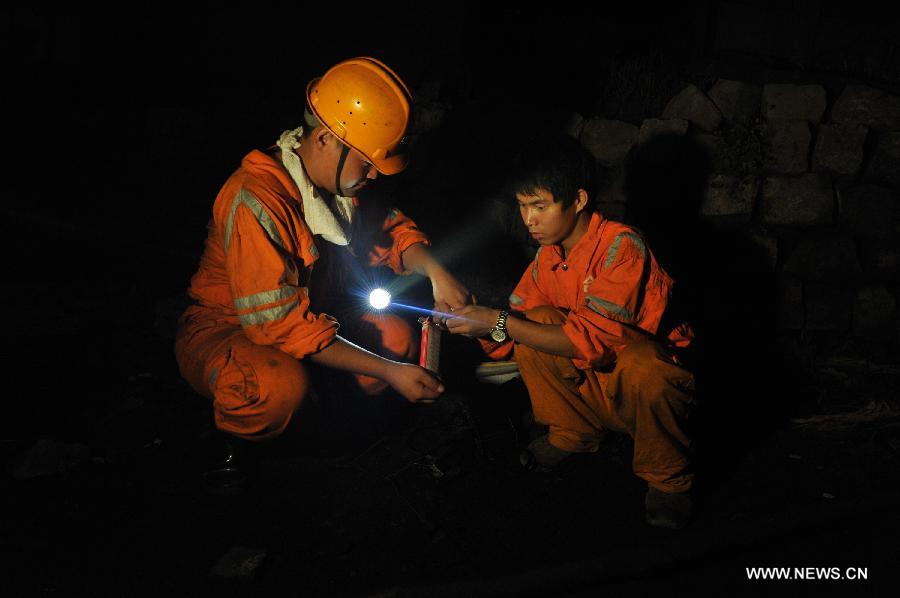 Cao Mingtao (L) and Zhong Hongliang monitor the concentration of carbon monoxide at the entrance to the Chengcheng sulfur mine in Chengcheng County, northwest China's Shaanxi Province, July 24, 2013. The mine caught fire Tuesday afternoon when 27 people were working underground. Seventeen of them had been rescued, while 10 others were confirmed dead early Wednesday. The fire started on an electric cable when workers were repairing air shaft facilities. (Xinhua/Ding Haitao) 