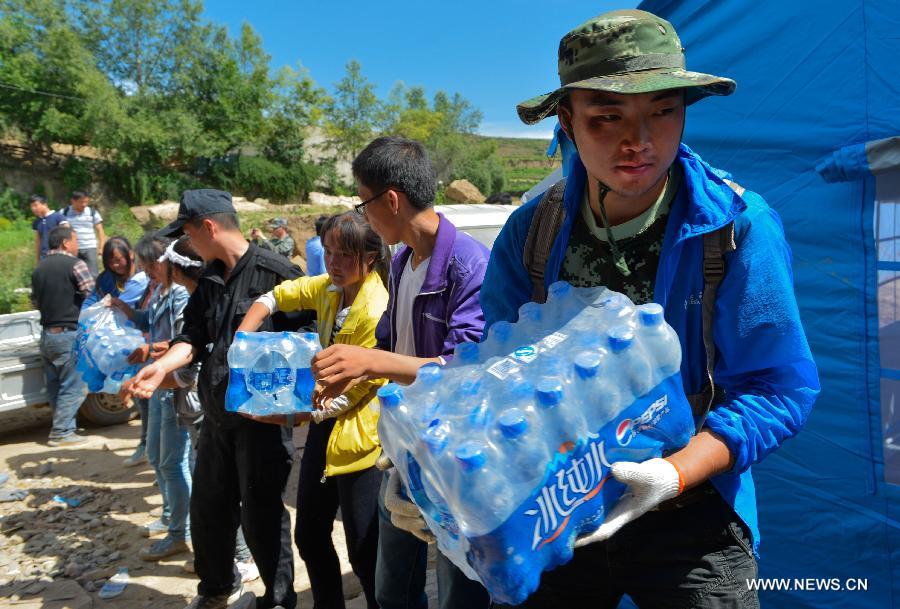 Volunteers help victims distribute the relief supplies in Yongxing Village of Minxian County, northwest China's Gansu Province, July 23, 2013. Volunteers are swarming into Dingxi after a 6.6-magnitude earthquake jolted a juncture region of Minxian County and Zhangxian County in Dingxi City of Gansu Monday morning.(Xinhua/Liu Xiao)