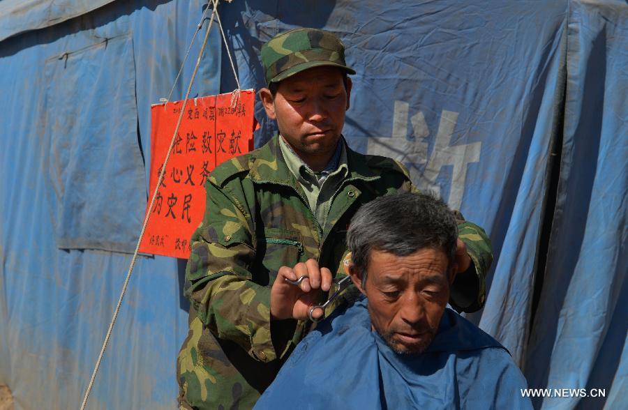 Volunteer Tan Maocheng cuts the hair of a local resident in the quake-hit Yongxing Village of Minxian County, northwest China's Gansu Province, July 23, 2013. Volunteers are swarming into Dingxi after a 6.6-magnitude earthquake jolted a juncture region of Minxian County and Zhangxian County in Dingxi City of Gansu Monday morning.(Xinhua/Liu Xiao)