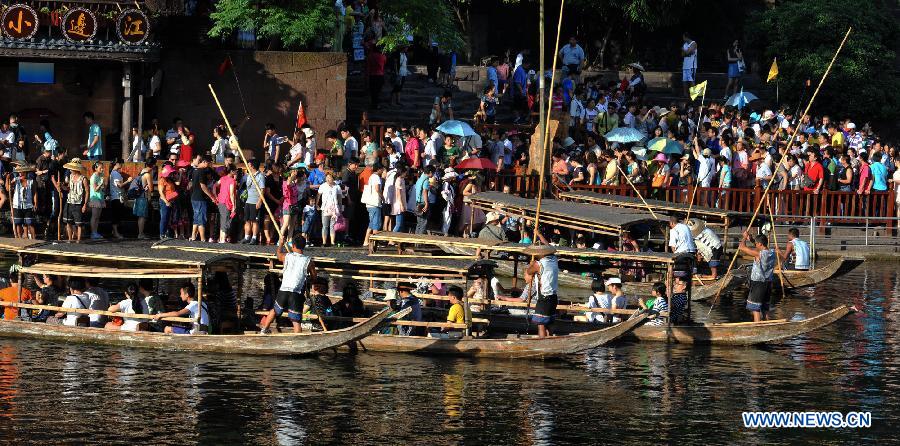 Tourists wait to board boats beside the Tuojiang River in the ancient town of Fenghuang in Fenghuang County of Xiangxi Tu and Miao Autonomous Prefecture, central China's Hunan Province, July 23, 2013. The tourist resort witnessed a travel peak in July, attracting 417,400 visitors till July 22, increasing by 28.79 percent year on year. (Xinhua/Long Hongtao)