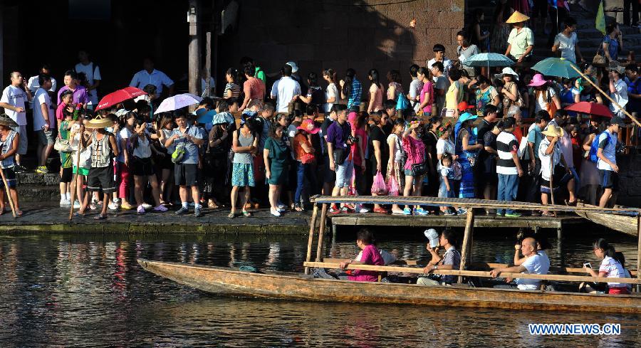 Tourists wait to board boats beside the Tuojiang River in the ancient town of Fenghuang in Fenghuang County of Xiangxi Tu and Miao Autonomous Prefecture, central China's Hunan Province, July 23, 2013. The tourist resort witnessed a travel peak in July, attracting 417,400 visitors till July 22, increasing by 28.79 percent year on year. (Xinhua/Long Hongtao)