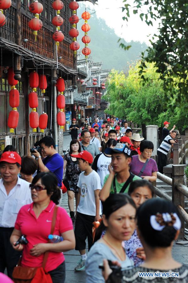 Tourists are seen in the ancient town of Fenghuang in Fenghuang County of Xiangxi Tu and Miao Autonomous Prefecture, central China's Hunan Province, July 23, 2013. The tourist resort witnessed a travel peak in July, attracting 417,400 visitors till July 22, increasing by 28.79 percent year on year. (Xinhua/Long Hongtao)