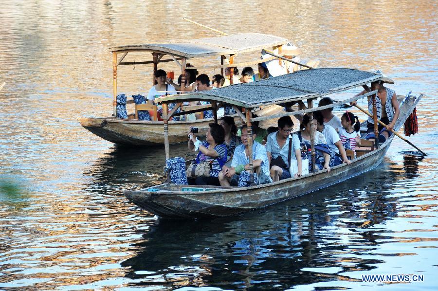 Tourists enjoy the scenery in boats on the Tuojiang River in the ancient town of Fenghuang in Fenghuang County of Xiangxi Tu and Miao Autonomous Prefecture, central China's Hunan Province, July 23, 2013. The tourist resort witnessed a travel peak in July, attracting 417,400 visitors till July 22, increasing by 28.79 percent year on year. (Xinhua/Long Hongtao)