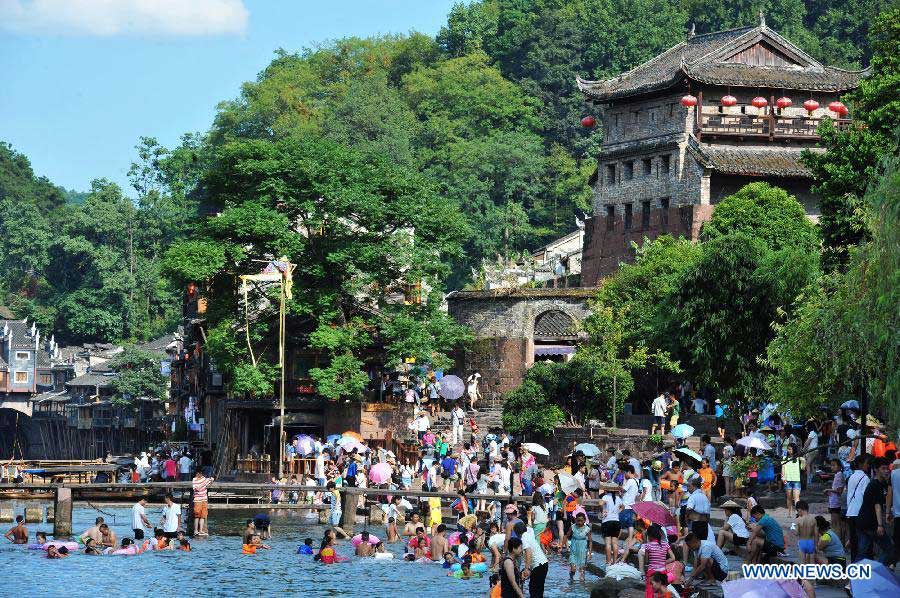 Tourists are seen in the ancient town of Fenghuang in Fenghuang County of Xiangxi Tu and Miao Autonomous Prefecture, central China's Hunan Province, July 23, 2013. The tourist resort witnessed a travel peak in July, attracting 417,400 visitors till July 22, increasing by 28.79 percent year on year. (Xinhua/Long Hongtao)