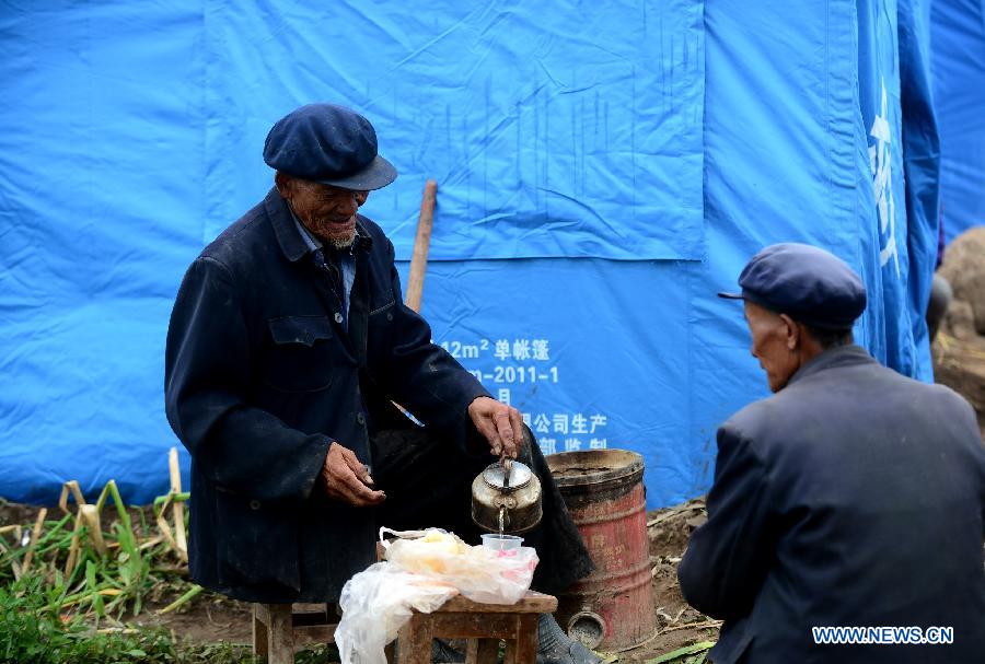 A villager makes tea outside a tent in quake-hit Yongxing Village of Minxian County, northwest China's Gansu Province, July 24, 2013. The death toll has climbed to 95 in the 6.6-magnitude earthquake which jolted a juncture region of Minxian County and Zhangxian County in Dingxi City Monday morning. (Xinhua/Zhang Meng)