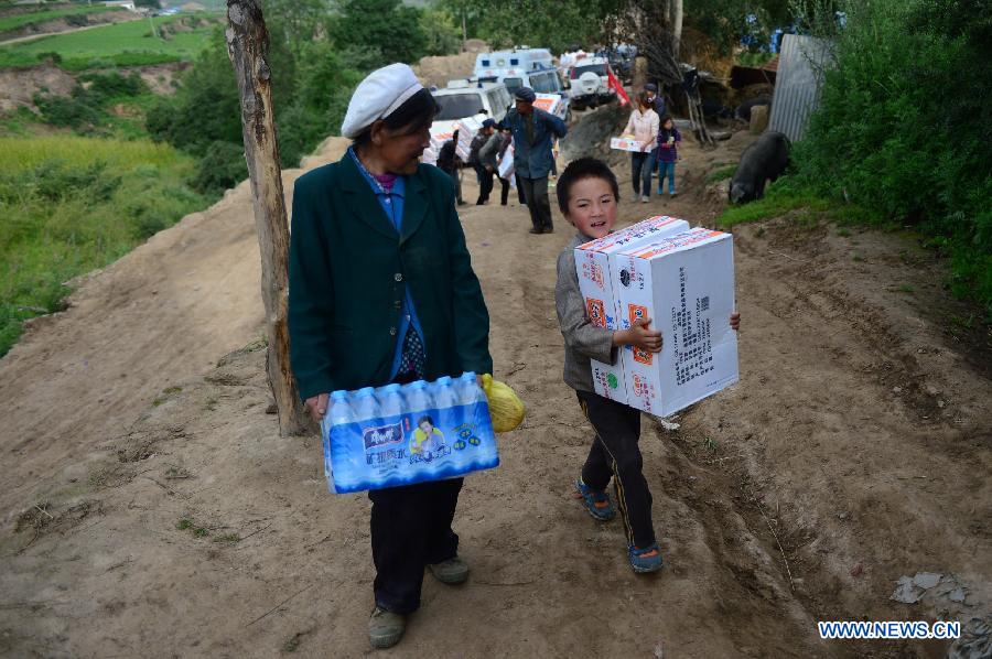 Villagers carry relief supplies in quake-hit Yongxing Village of Minxian County, northwest China's Gansu Province, July 24, 2013. The death toll has climbed to 95 in the 6.6-magnitude earthquake which jolted a juncture region of Minxian County and Zhangxian County in Dingxi City Monday morning. (Xinhua/Zhang Meng)