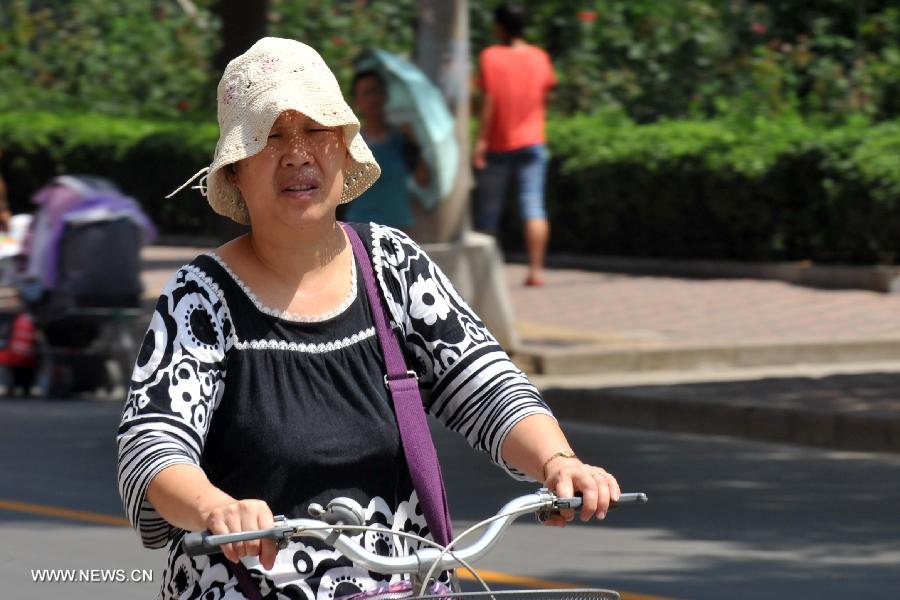 A citizen rides on a road as heat wave hits Shijiazhuang, north China's Hebei Province, July 24, 2013. The highest temperature in some areas of Hebei Province was forecasted to reach 37 degrees Celsius on Wednesday. (Xinhua/Zhu Xudong) 