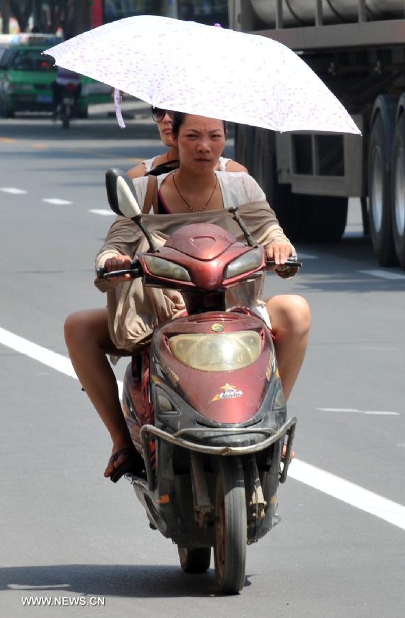 Citizens ride on a road as heat wave hits Shijiazhuang, north China's Hebei Province, July 24, 2013. The highest temperature in some areas of Hebei Province was forecasted to reach 37 degrees Celsius on Wednesday. (Xinhua/Zhu Xudong)