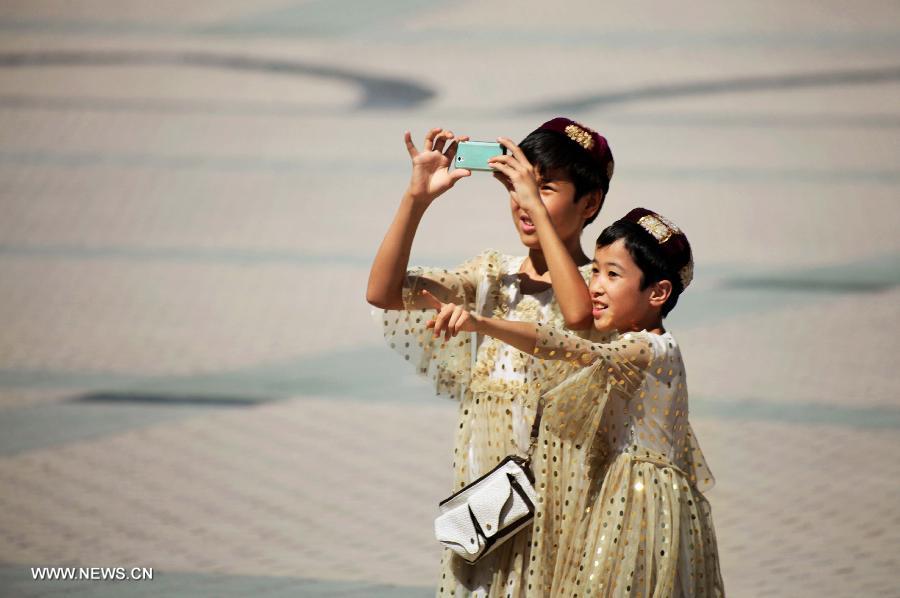 Children take photos in the Id Kah Square in Kashgar, northwest China's Xinjiang Uygur Autonomous Region, July 16, 2013.(Xinhua/Gao Wenfeng)