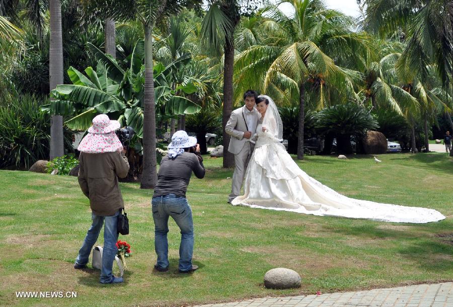 Couples pose for wedding photos on the beach in Sanya, south China's Hainan Province, July 24, 2013. (Xinhua/Wang Junfeng)