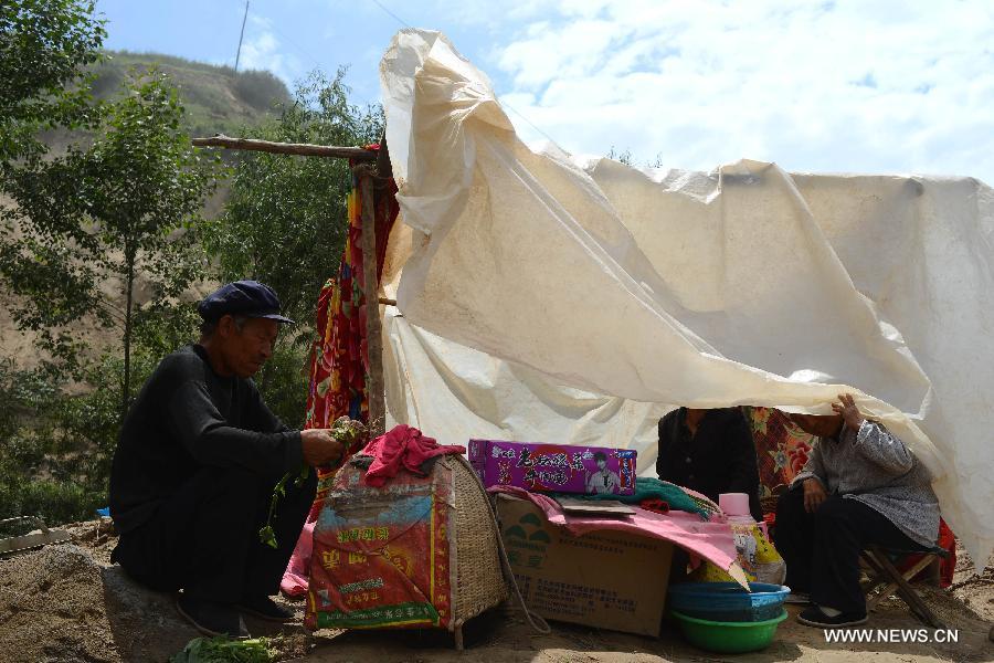 Displaced villagers sit in a makeshift tent in the quake-hit Meichuan Township, Minxian County, northwest China's Gansu Province, July 24, 2013. Due to a lack of tents, almost ten people could share one in the township. The Ministry of Civil Affairs dispatched more tents and quilts to the quake zone of Gansu on Tuesday evening. A 6.6-magnitude quake jolted the juncture of Minxian and Zhangxian counties in the city of Dingxi at 7:45 a.m. Monday, leaving at least 95 people dead as of Tuesday evening. (Xinhua/Jin Liangkuai)