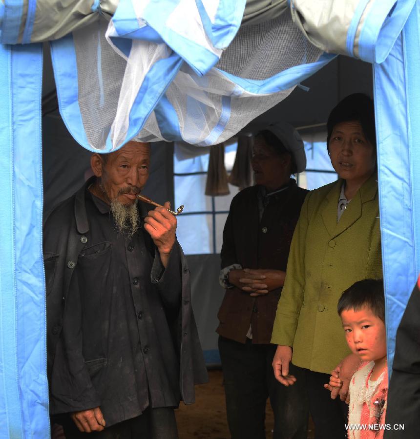 Villagers stand in a makeshift tent in the quake-hit Majiagou Village, Meichuan Township, Minxian County, northwest China's Gansu Province, July 24, 2013. Due to a lack of tents, almost ten people could share one in the township. The Ministry of Civil Affairs dispatched more tents and quilts to the quake zone of Gansu on Tuesday evening. A 6.6-magnitude quake jolted the juncture of Minxian and Zhangxian counties in the city of Dingxi at 7:45 a.m. Monday, leaving at least 95 people dead as of Tuesday evening. (Xinhua/Jin Liangkuai)