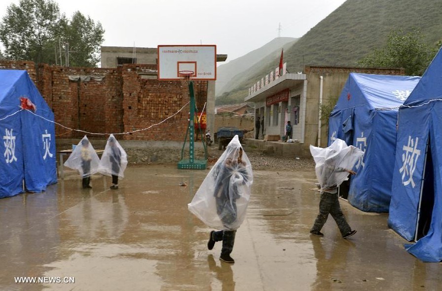 Children play in rain at a temporary settlement for quake-affected people in Qingtu Village of Minxian County, northwest China's Gansu Province, July 24, 2013. A rainfall hit the quake-jolted region in Gansu on Wednesday. The death toll has climbed to 95 in the 6.6-magnitude earthquake which jolted a juncture region of Minxian County and Zhangxian County in Dingxi City Monday morning. (Xinhua/Liu Xiao)