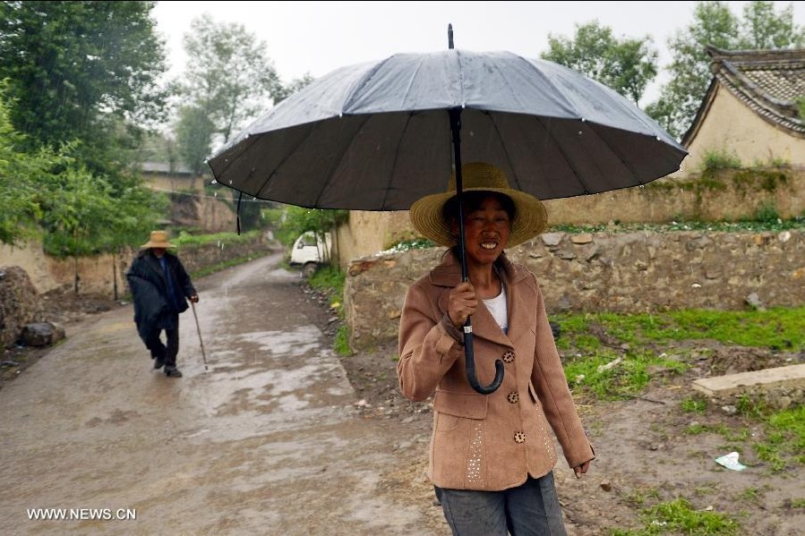 A woman walks in rain in quake-hit Qingtu Village of Minxian County, northwest China's Gansu Province, July 24, 2013. A rainfall hit the quake-jolted region in Gansu on Wednesday. The death toll has climbed to 95 in the 6.6-magnitude earthquake which jolted a juncture region of Minxian County and Zhangxian County in Dingxi City Monday morning. (Xinhua/Liu Xiao)
