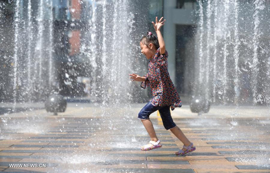 A young girl cools off in a fountain in Beijing, capital of China, July 24, 2013. A heat wave hit Beijing on Wednesday, with the highest temperature reaching 36 degrees Celsius. (Xinhua/Li Xin)