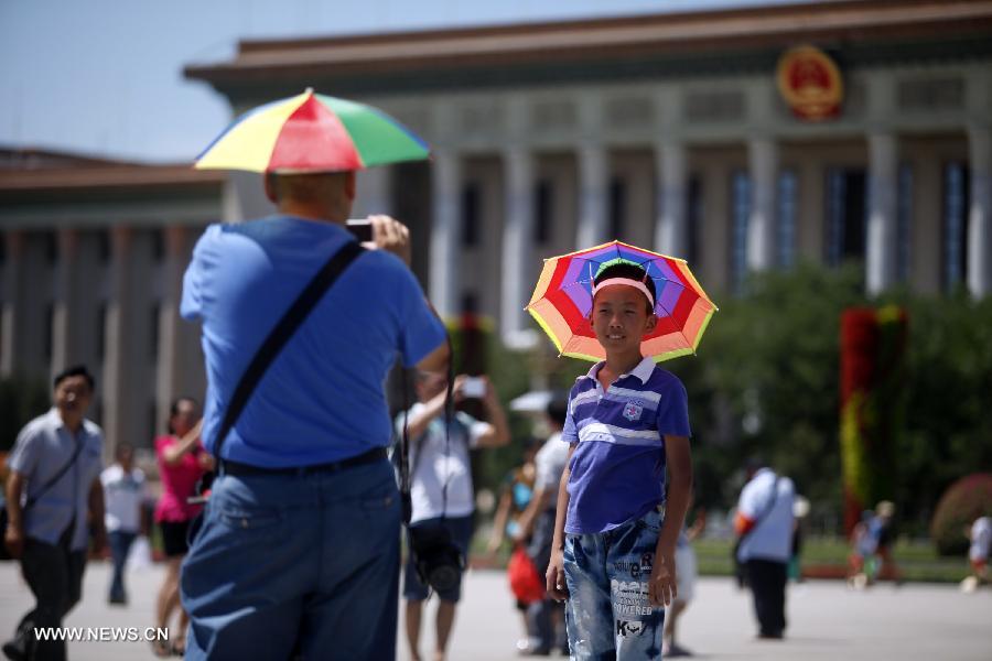 A young boy wearing a special umbrella on the head poses for a photo at the Tian'anmen Square in Beijing, capital of China, July 24, 2013. A heat wave hit Beijing on Wednesday, with the highest temperature reaching 36 degrees Celsius. (Xinhua/Yang Le) 