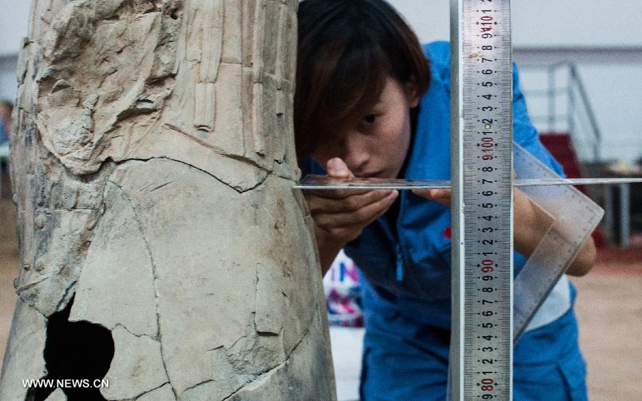 An archeological worker measures a nearly-repaired terracotta warrior at the Emperor Qinshihuang's Mausoleum Site Museum in Xi'an, capital of northwest China's Shaanxi Province, July 18, 2013. The 2,200-year-old mausoleum was discovered in Lintong District, 35 km east of Xi'an, in 1974 by peasants who were digging a well. The Chinese terracotta army buried around the mausoleum was one of the greatest archeological finds of modern times. (Xinhua/Xue Yanwen) 