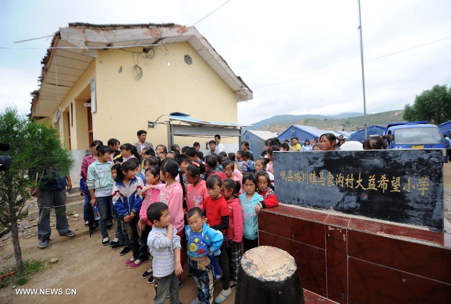 Pupils wait for relief goods at the entrance to a primary school in the quake-hit Majiagou Village in Meichuan Township, Minxian County, northwest China's Gansu Province, July 24, 2013. Over 360 schools in Gansu's Minxian and Zhangxian counties were destroyed by the 6.6-magnitude quake that occurred on Monday, affecting 77,000 students, according to the local authorities. (Xinhua/Luo Xiaoguang)