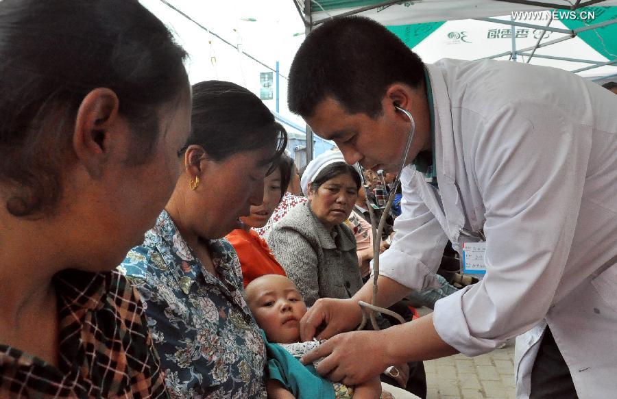 A doctor gives a child medical checkup in a makeshift clinic in Meichuan Town of Minxian County, northwest China's Gansu Province, July 24, 2013. By far, makeshift clinics have been set up to offer basic medical treatment in quake-hit towns. And severely injured people have been sent to hospitals for better care in the county seat of Minxian, Dingxi City and Lanzhou City, capital of Gansu. (Xinhua/Guo Gang) 