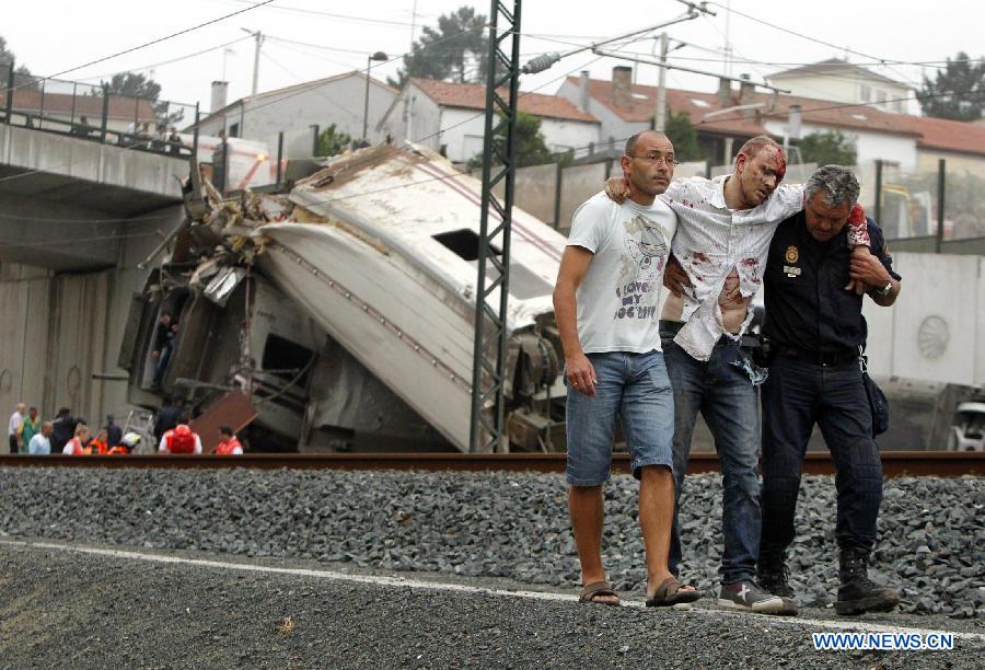 A citizen and a local police member rescue a survivor at the site where a train crashed, at the entrance of the Santiago de Compostela Station, in the autonomous community of Galicia, northwest of Spain, on July 24, 2013. Up to 35 people have died and around 100 injured after a train derailed just outside the city of Santiago de Compostela in the region of Galicia in north-western Spain on Wednesday evening. (Xinhua/La Voz de Galicia)