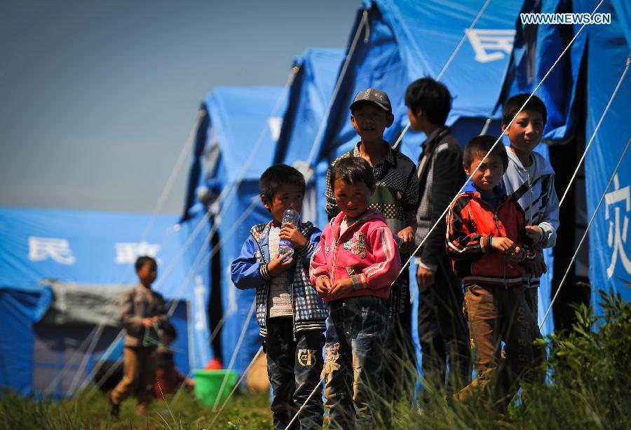 Children look on at a makeshift settlement in Meichuan Town of quake-hit Minxian County, northwest China's Gansu Province, July 23, 2013. A 6.6-magnitude quake hit northwest China's Gansu Province on Monday morning, leaving 95 dead and 1,001 injured. (Xinhua/Liu Xiao) 