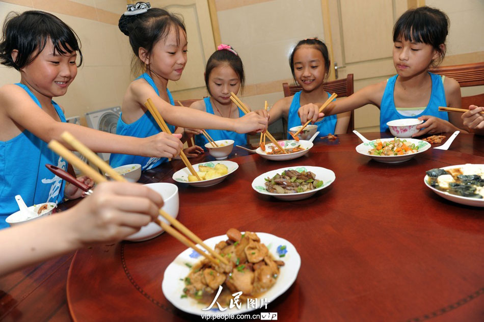 Staff serves the children with their lunch in the cafeteria in Yuyao City, east China’s Zhejiang province. (Photo by Chen Binrong/ vip.people.com.cn)