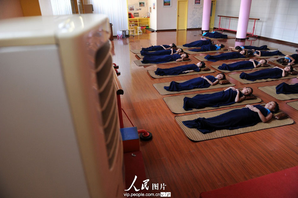 Children of migrant workers take a nap in the air-conditioned room during the lunch break in Yuyao City, east China’s Zhejiang province. (Photo by Chen Binrong/ vip.people.com.cn)