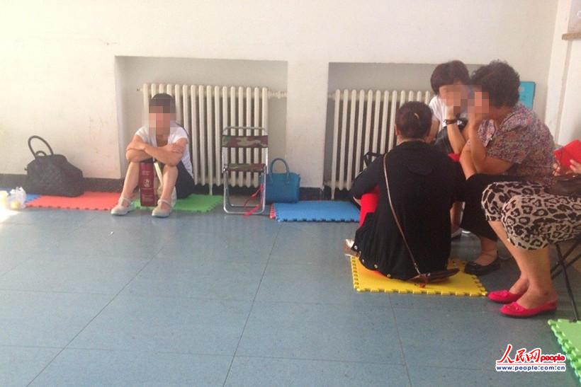 The infant’s mother (first from left) waits anxiously outside the ward. (People’s Daily Online/Weng Fanqi) 