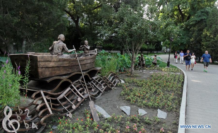 A sculpture named "Let us sway twin oars" attracts lots of tourists at the Beihai Park in Beijing, capital of China, July 25, 2013. The sculpture is in memory of a Chinese popular song of the same name. (Xinhua/Li Xin) 