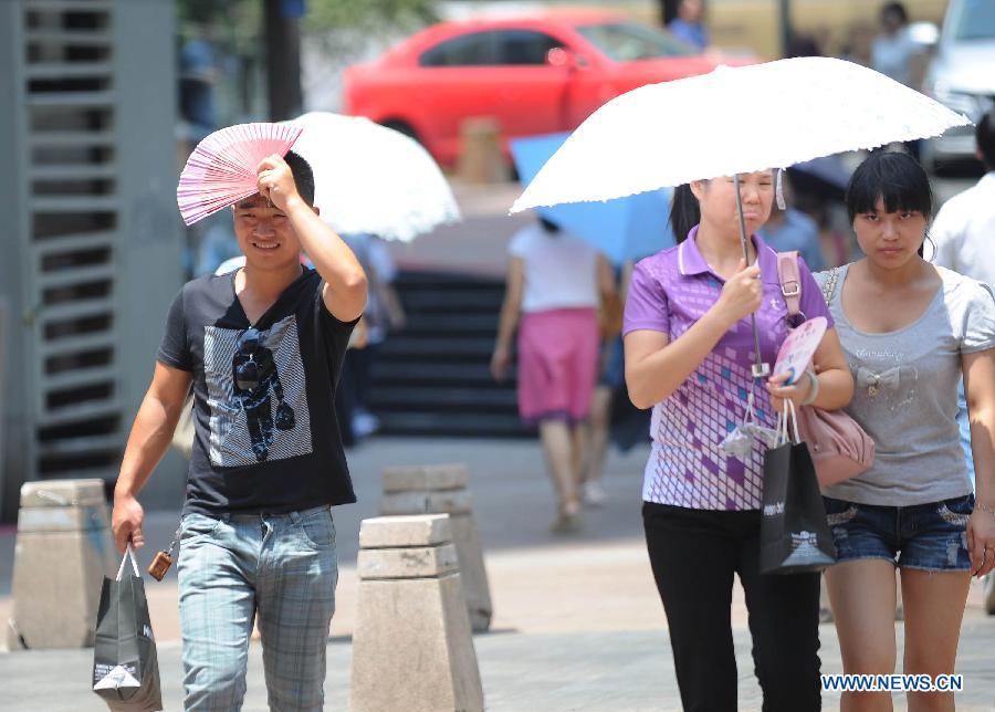 Citizens walk on a street in southwest China's Chongqing municipality, July 26, 2013. Local meteorological observatory Friday issued a red alert for high temperature, warning that the highest temperature will reach 40 degrees Celsius in some areas. (Xinhua/Li Jian)