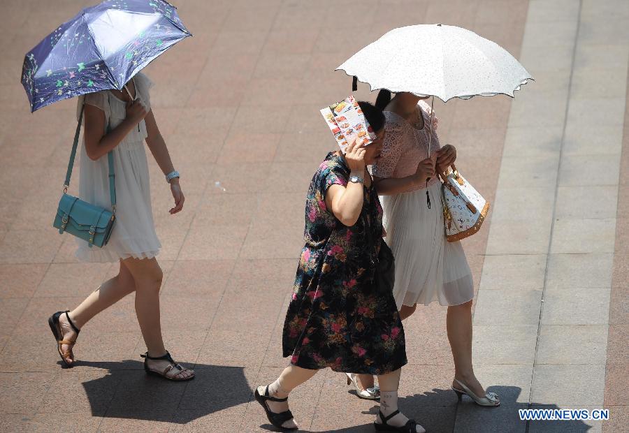 Citizens walk in on a street in southwest China's Chongqing municipality, July 26, 2013. Local meteorological observatory Friday issued a red alert for high temperature, warning that the highest temperature will reach 40 degrees Celsius in some areas. (Xinhua/Li Jian)