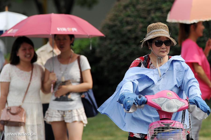 Women holding umbrella or wearing hat and glasses to shield them from the heating sun in Hangzhou, capital of east China's Zhejiang Province, July 26, 2013. A lingering hot wave hit the city, with the highest temperature reaching above 40 degrees Celsius in these three days. (Xinhua/Ju Huanzong)