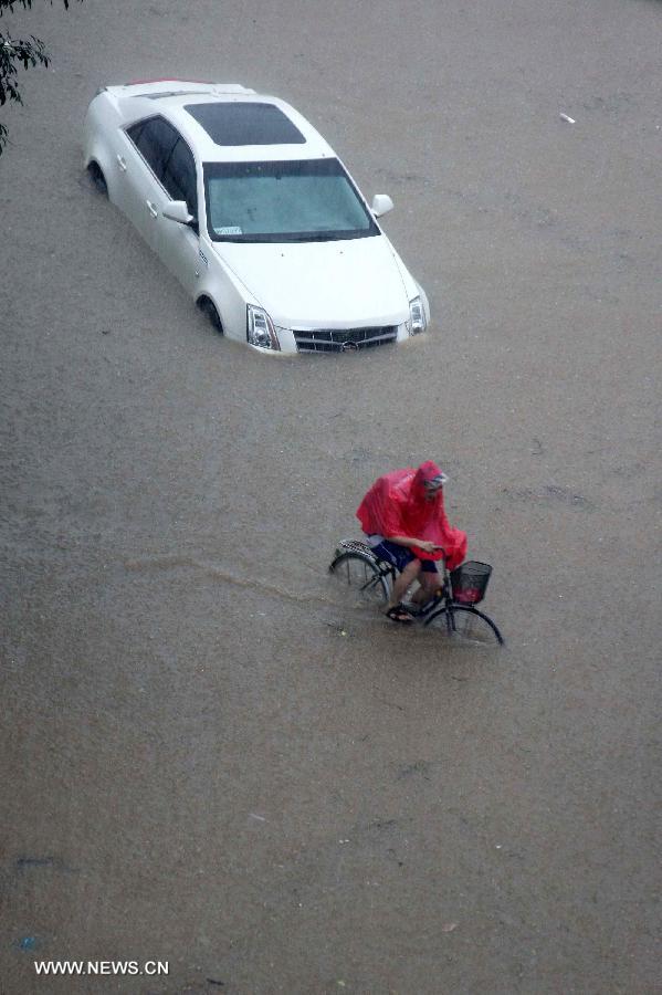 A citizen rides on a flooded road in Liaocheng City, east China's Shandong Province, July 26, 2013. Rainstorms hit the city from Thursday evening to Friday. (Xinhua/Zhang Xianju)
