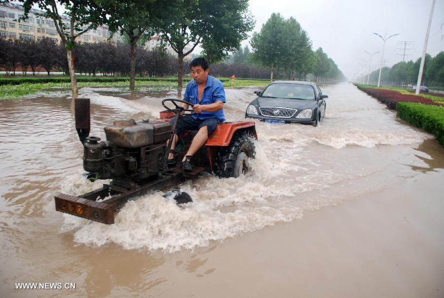 A tractor pulls a car which broke down on a flooded road in Liaocheng City, east China's Shandong Province, July 26, 2013. Rainstorms hit the city from Thursday evening to Friday. (Xinhua/Xu Jinsong)