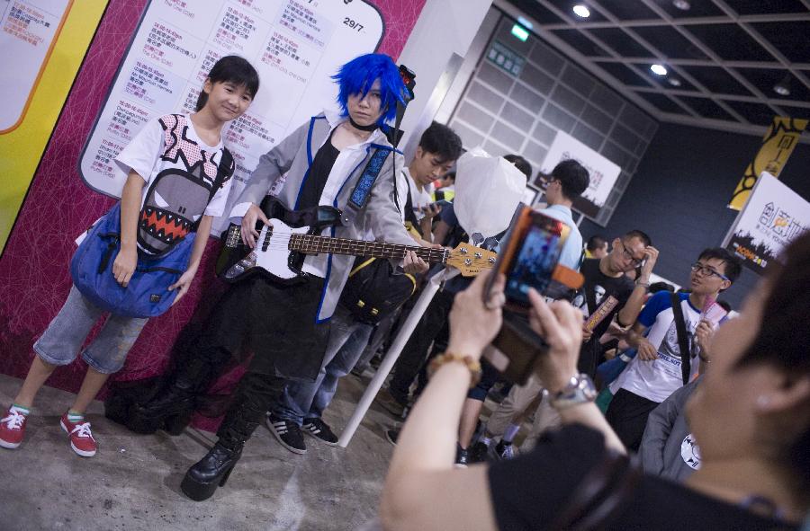 A girl poses for a photo with a cosplayer at the Animation, Comics & Games Expo in Hong Kong (ACGHK), south China, July 26, 2013. The five-day ACGHK, starting here Friday, is expected to attract some 700,000 visitors. (Xinhua/Zhao Yusi) 