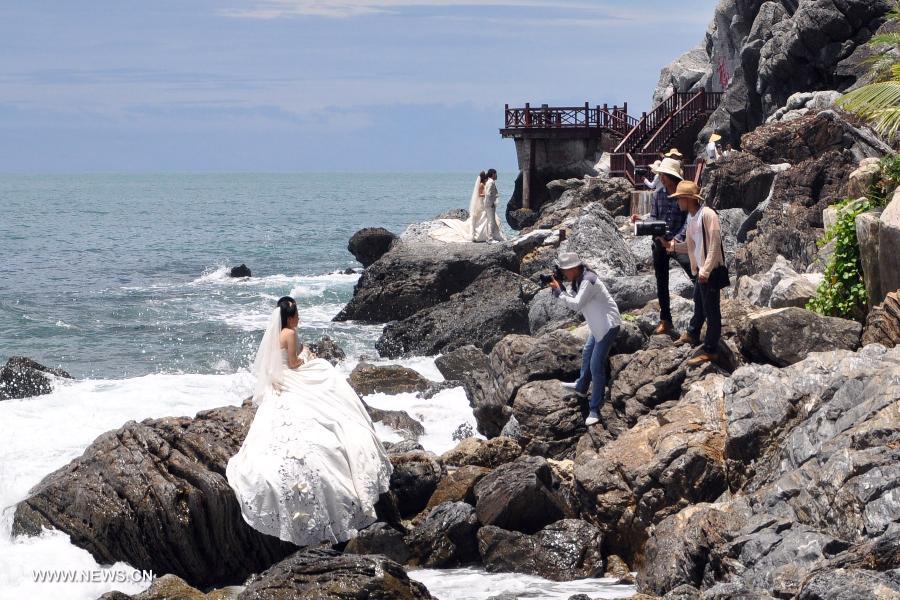 Couples pose for wedding photos on the beach in Sanya, south China's Hainan Province, July 24, 2013. (Xinhua/Wang Junfeng)