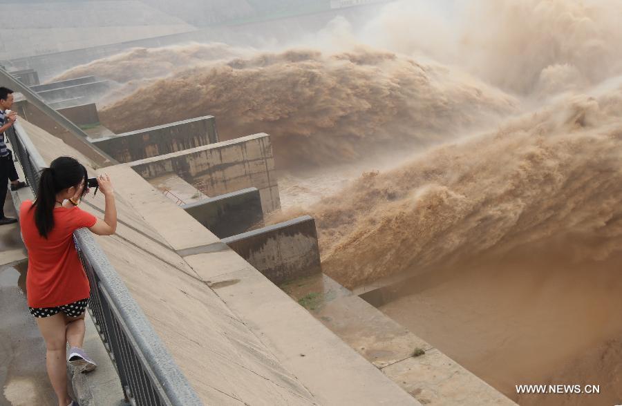 Tourists watch water gushing out from the Xiaolangdi Reservoir on the Yellow River during a sand-washing operation in Luoyang, central China's Henan Province, July 23, 2013. The on-going operation works by discharging water at a volume of 2,000 cubic meters per second from the reservoir to clear up the sediment in the Yellow River , the country's second-longest waterway. Speeding currents would carry tons of sand into the sea. The Yellow River has been plagued by an increasing amount of mud and sand. Each year, the river bed rises as silt deposits build up, slowing the water flow in the lower reaches. (Xinhua/Zhang Xiaoli)