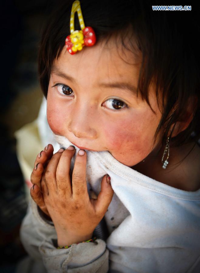 A girl looks on at a makeshift settlement in Meichuan Town of quake-hit Minxian County, northwest China's Gansu Province, July 23, 2013. A 6.6-magnitude quake hit northwest China's Gansu Province on Monday morning, leaving 95 dead and 1,001 injured. (Xinhua/Liu Xiao)